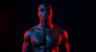 A man with no shirt on in front of a black background photo