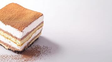 A delicious square piece of tiramisu dessert is presented on a white background with cocoa powder dusting it beautifully. photo