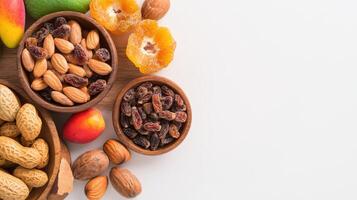 A vibrant overhead shot showcases various nutritious snacks including almonds raisins peanuts dried mango and dried apricots arranged in small wooden bowls on a white background photo
