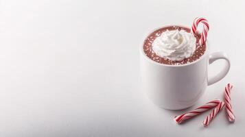 A delicious cup of hot chocolate topped with whipped cream and a candy cane sits on a white background perfect for winter holiday themed designs and advertisements. photo