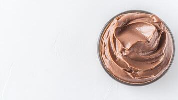 A rich and decadent chocolate cream dessert filling sits in a clear glass bowl on a white background perfect for culinary websites or dessert recipes. photo