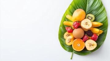 A vibrant assortment of fresh tropical fruits including mango, kiwi, banana, strawberry, and orange slices artfully arranged on a large green leaf against a clean white background. photo