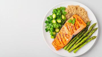 A healthy and delicious grilled salmon fillet is served with quinoa, asparagus, and Brussels sprouts on a white plate for a balanced meal. photo
