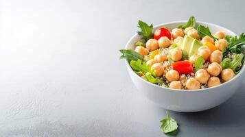 A vibrant and healthy quinoa salad bowl brimming with chickpeas, avocado, cherry tomatoes, and fresh greens sits on a gray background offe a delicious and nutritious meal photo