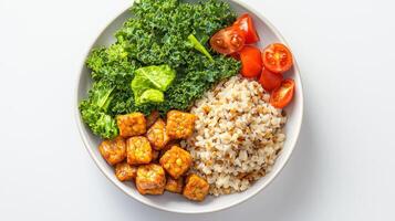 A healthy and delicious meal featu pan-fried tempeh cubes served alongside fluffy brown rice, vibrant kale, and ripe cherry tomatoes in a stylish bowl. photo