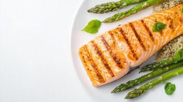 Grilled salmon fillet served with roasted asparagus and quinoa on a white plate perfect for a healthy and delicious meal. photo