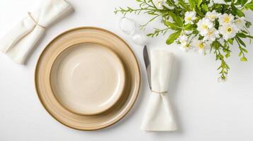 A stylish table setting features a beige dinner plate and bowl with linen napkins flowers and silverware on a white background perfect for sp or summer gathes. photo