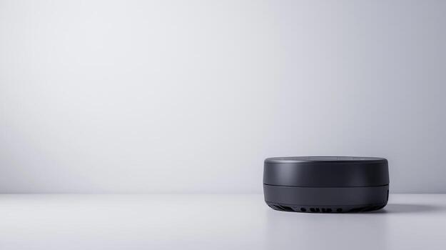 A black speaker sitting on a table in front of a white wall photo