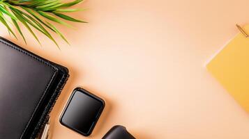 Black leather notebook, phone, pen, and other office supplies on a pink background photo