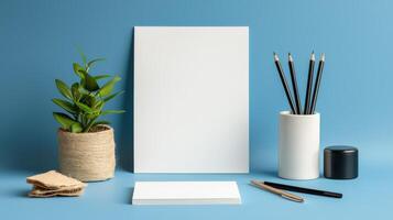 Blank white paper, pencils, and a plant on a blue background photo