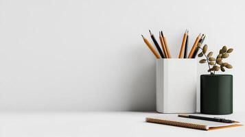 A vase with pencils, a notebook and a plant on a white table photo