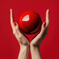 A woman's hands holding a red ball on a red background photo