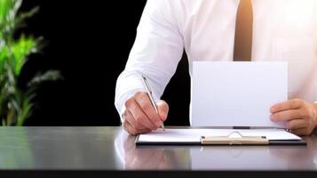 Businessman writing on blank paper with pen on desk photo