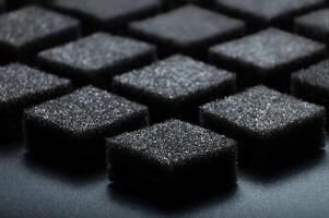 Black foam texture as background, side view. Sponge surface. Abstract black porous layers folded into a symmetrical pattern photo