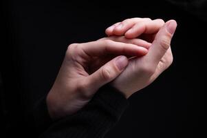 Close-up image of beautiful female hands with delicate pink manicure on nails on black background. Hand skin care, manicure and beauty treatments. Elegant and graceful hands with thin graceful fingers photo