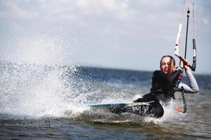 A view through a telephoto lens of a kitesurfer doing a trick with a darkslide. Focus on the splashes. The athlete is out of focus photo