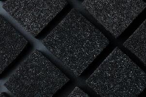Black Cubes of flexible foam sponges laid out in a pattern. Macro close-up in soft focus. Abstract cubic background photo