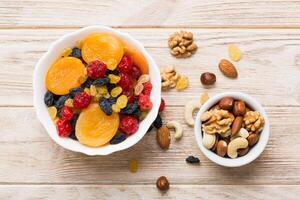 healthy snack mixed nuts and dried fruits in bowl on table background, almond, pineapple, cranberry, cherry photo