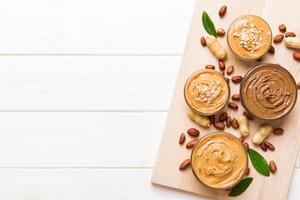 Glass jar with peanut butter on table background, top view space for text photo