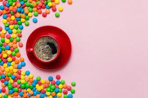 Coffee cup with chocolates and colored candy. Top view table background photo