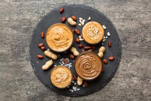 Glass jar with peanut butterin plate on table background, top view space for text and close up photo