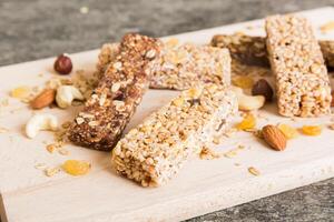 Various granola bars on table background. Cereal granola bars. Superfood breakfast bars with oats, nuts and berries, photo
