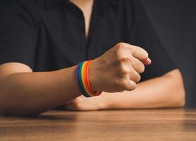 Hand fist with rainbow wristband in a hand while sitting on a black background photo
