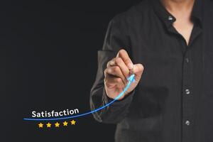Businessman drawing a line symbol increases satisfaction and feedback while standing on a black background photo