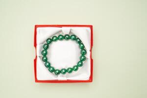 Top view of jade bangle or bracelet in a red box on a green background. photo