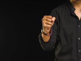 Hand fist with rainbow wristbands in a hand while standing against a black background photo