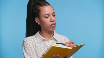 Focused student writing notes in notebook on blue background video
