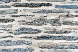 Close up of part of old stone wall with flat grey slate stones and mortar, textured and rustic background suitable for architectural and construction projects, photo