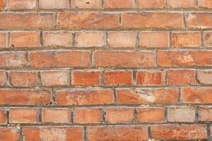 Red brick wall showing signs of age and weathering, with a random pattern, creates a textured and rustic backdrop, giving a sense of history, photo