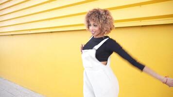 A Joyful Woman Enthusiastically Dancing in Front of a Vibrant and Bright Yellow Wall video