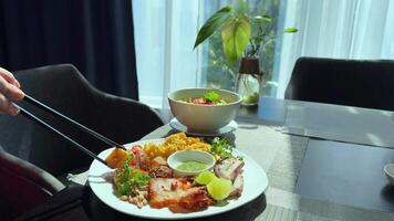 delicious asian lunch dish dinner soup and plate of meat fish sauce eat with chopsticks sunny day dip a piece of baked potato in plate lime meat greens salad video