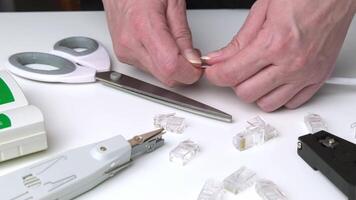 Close-up of hands cutting Ethernet cable wires on white desk with networking tools scattered around video