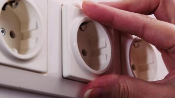 Close-up of Hand Using Screwdriver to Mount Electrical Socket on White Wall in Home Setting video