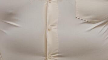 Close-up of a man's chest in a tight beige button-up shirt showing fabric texture and chest detail video