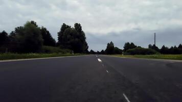 POV Low Angle View of Driving on an Open Road with Overcast Sky and Lush Greenery video