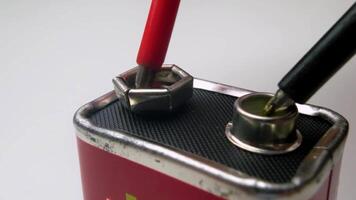 Close-Up View of Electrical Testing Probes Connected to a Vintage 9V Battery in a Minimalist Setting video
