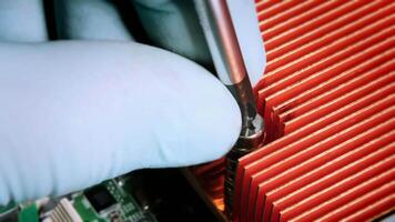 Close-up of a screwdriver securing a red heat sink onto a computer motherboard, highlighting computer assembly and cooling components. video