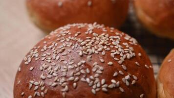 Close-up view of freshly baked golden brown burger buns with sesame seeds on a cooling rack in a cozy home kitchen setting video
