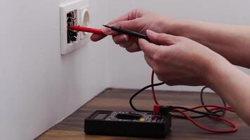 Professional Hand Testing Electrical Wall Socket with Digital Multimeter on Wooden Surface in Modern Interior video