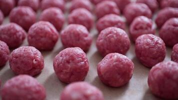 Close-up of Freshly Prepared Raw Meatballs Arranged on Parchment Paper in a Kitchen Setting video