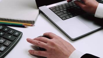 Close-up of a businessperson using a laptop with a calculator, notebook, and pencils on the desk, highlighting office work and financial tasks. video