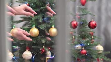 Hands Decorating a Festive Christmas Tree with Shiny Ornaments in a Cozy Indoor Setting video