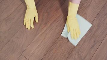 Person Wearing Yellow Gloves Cleaning Modern Wooden Floor with Cloth in Indoor Home Setting video