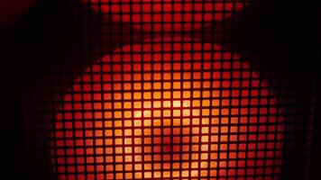 Close-up of red and orange light glowing behind a mesh grid, creating an abstract and industrial visual effect. video