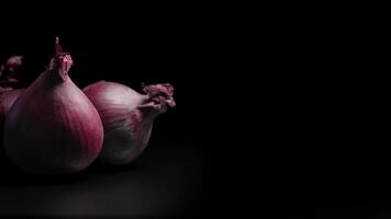 Close-up of Three Red Onions on Dark Background Highlighting Natural Texture and Color in a Still Life Composition video