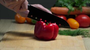Close-up of hands skillfully slicing fresh red bell pepper on wooden cutting board in a vibrant kitchen setting video